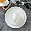 Kubek porcelanowy z koronkowym wzorem leżący na talerzach