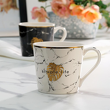 Kubek porcelanowy z marmurowym wzorem i złotym liściem monstery, na kubku jest napis simple life