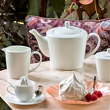 czajnik, cukiernica, mlecznik i filiżanka z białej porcelany na stole