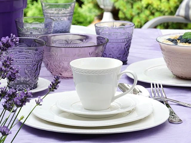 filiżanka porcelanowa na talerzach i fioletowe szklanki